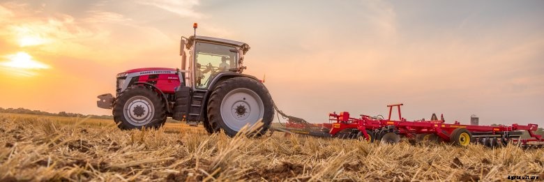 Massey Ferguson 8S tractor pulling tillage equipment at sunset